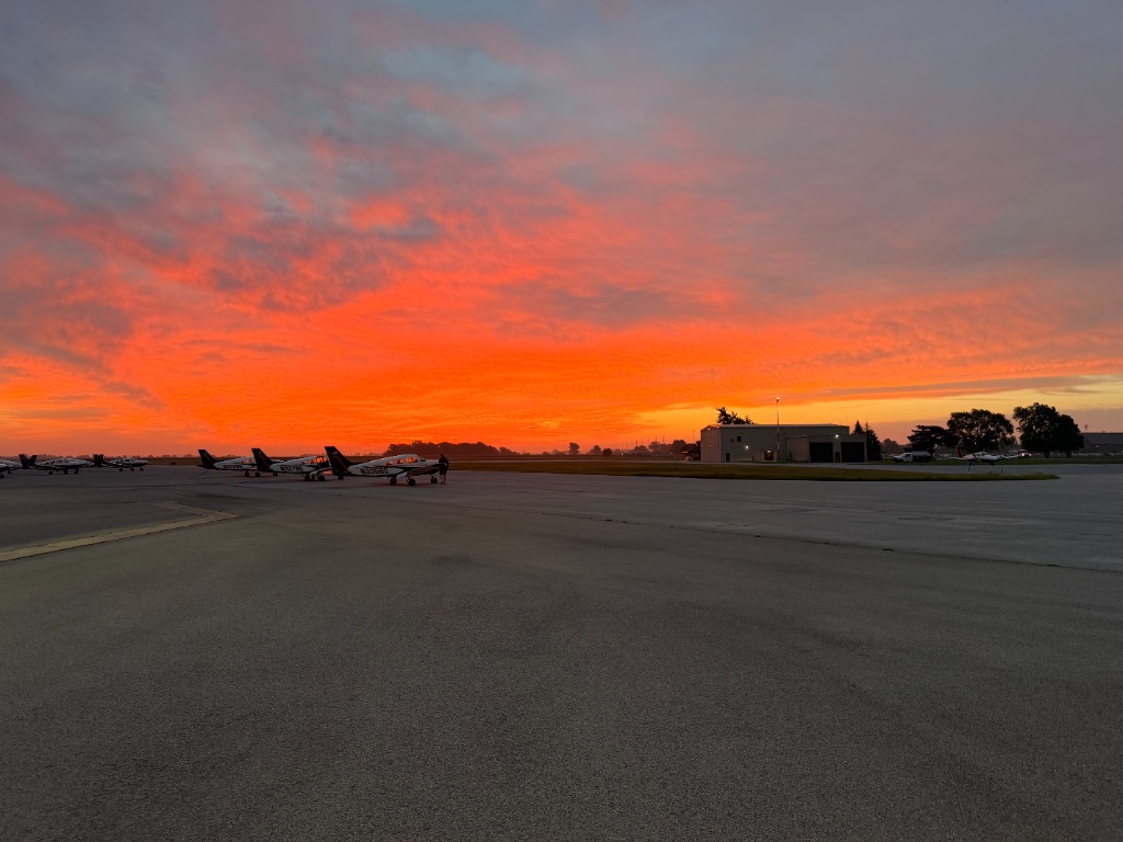 Airfield apron and flight line under vivid orange sunset