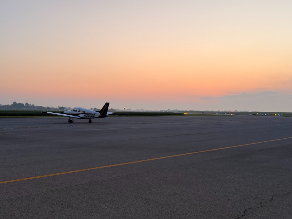 Flight training aircraft staged on runway during golden sunrise